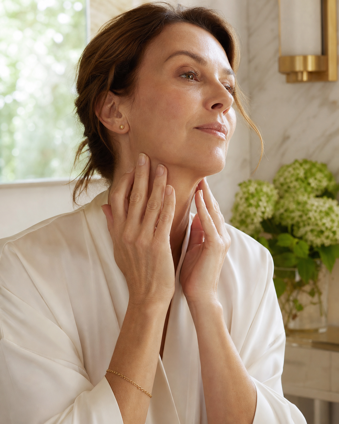 Midlife woman applying face, neck and décolleté serum along her jawline and neck